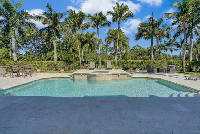 view of pool with a patio area, a pool with connected hot tub, and fence