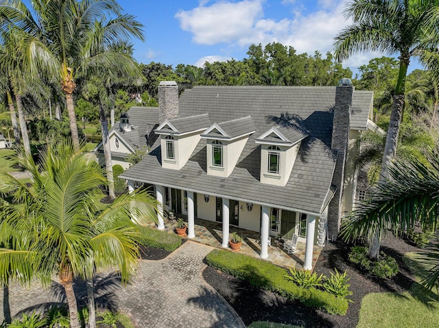 view of front of home featuring decorative driveway, a chimney, and stucco siding