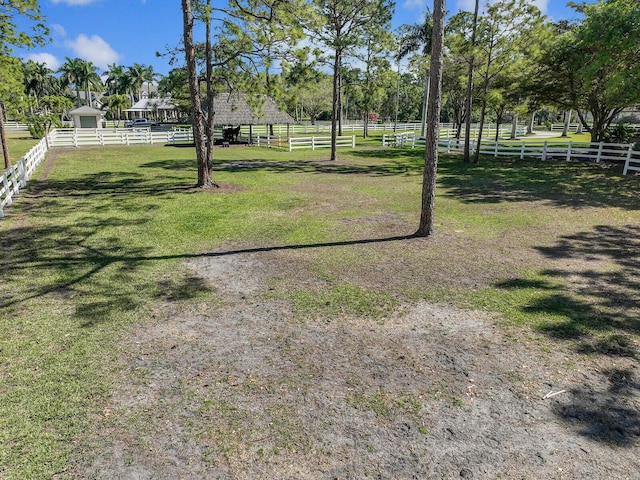 view of yard featuring an enclosed area, a rural view, and fence