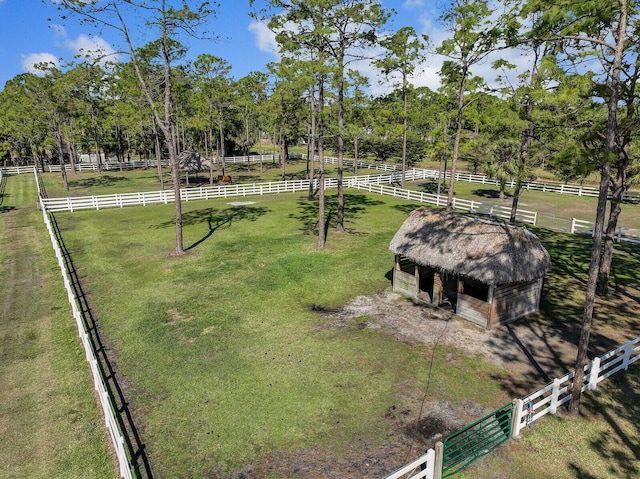 view of community with an outbuilding, a rural view, fence, and a lawn