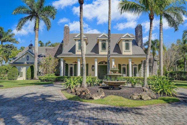 view of front of house featuring a chimney, decorative driveway, and stucco siding