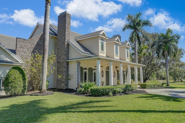 view of front of house featuring stucco siding, a chimney, and a front yard