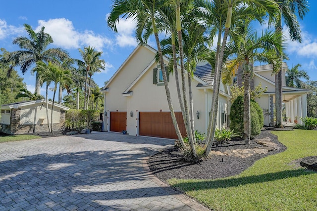 view of home's exterior with decorative driveway, a yard, and stucco siding