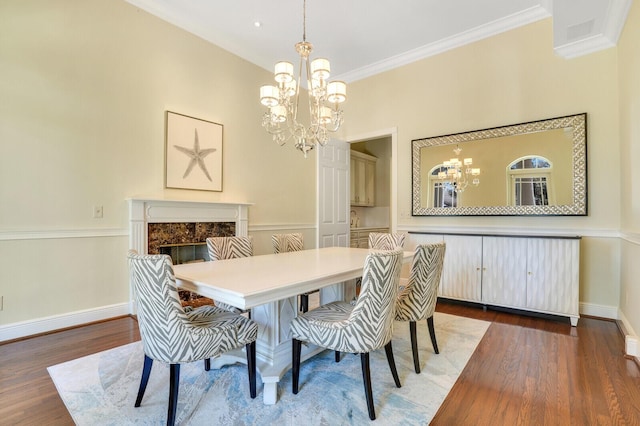 dining area featuring a chandelier, a premium fireplace, wood finished floors, baseboards, and ornamental molding