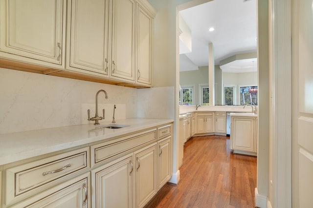 kitchen featuring tasteful backsplash, cream cabinets, a sink, and light wood-style floors