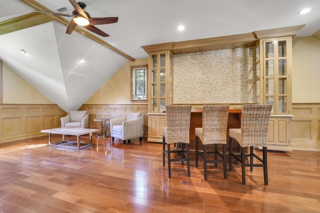 interior space featuring a wainscoted wall, vaulted ceiling, visible vents, and wood finished floors