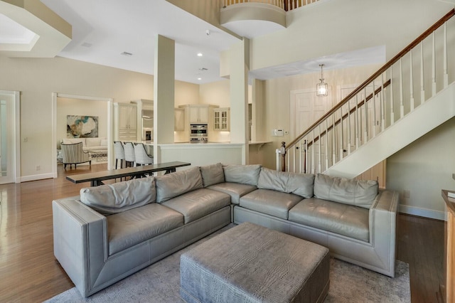 living area with baseboards, wood finished floors, and stairs
