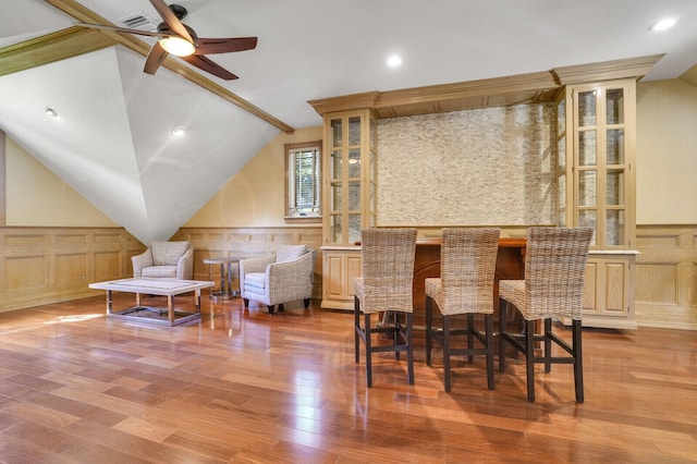 interior space with a dry bar, vaulted ceiling, a wainscoted wall, and ceiling fan