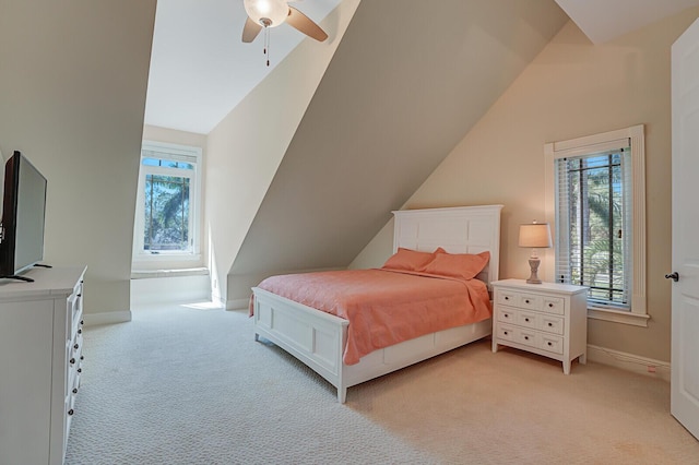 bedroom with vaulted ceiling, light colored carpet, and multiple windows