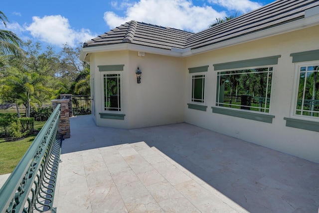 view of side of home featuring a patio area, a tiled roof, and stucco siding