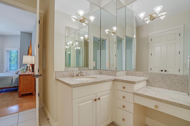 ensuite bathroom with tile patterned floors, baseboards, an inviting chandelier, vanity, and connected bathroom