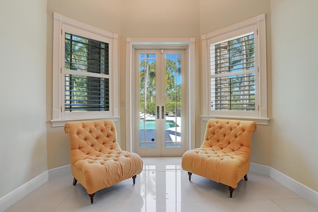 living area with french doors, baseboards, and tile patterned flooring