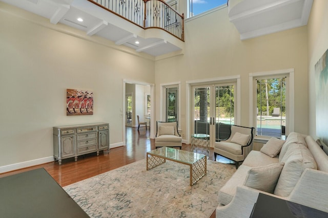 living room featuring baseboards, a towering ceiling, wood finished floors, french doors, and beam ceiling