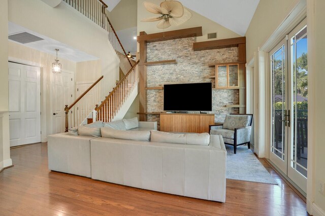 living area featuring wood finished floors, visible vents, high vaulted ceiling, and stairway