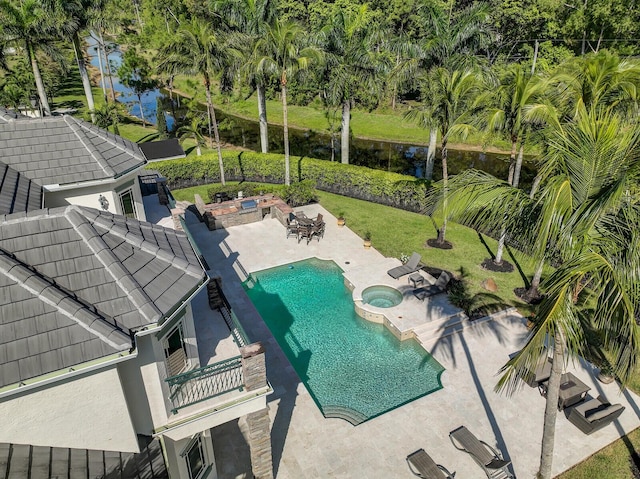 view of pool with a patio, a fire pit, an in ground hot tub, a water view, and a yard