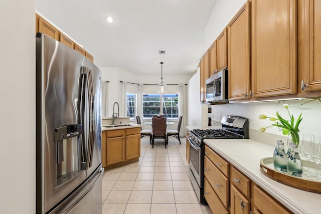 kitchen with appliances with stainless steel finishes, light countertops, a sink, and light tile patterned floors