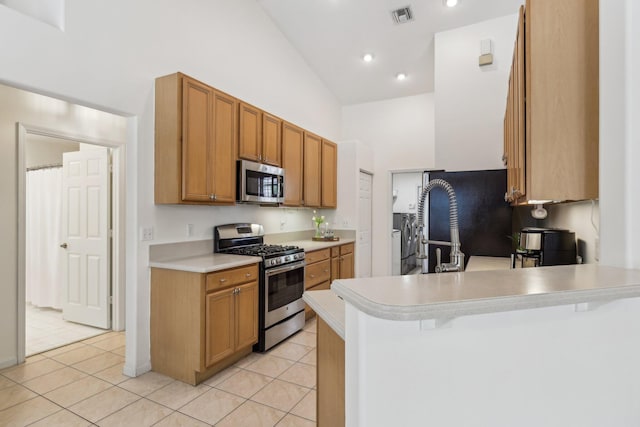 kitchen featuring light countertops, visible vents, appliances with stainless steel finishes, separate washer and dryer, and a peninsula