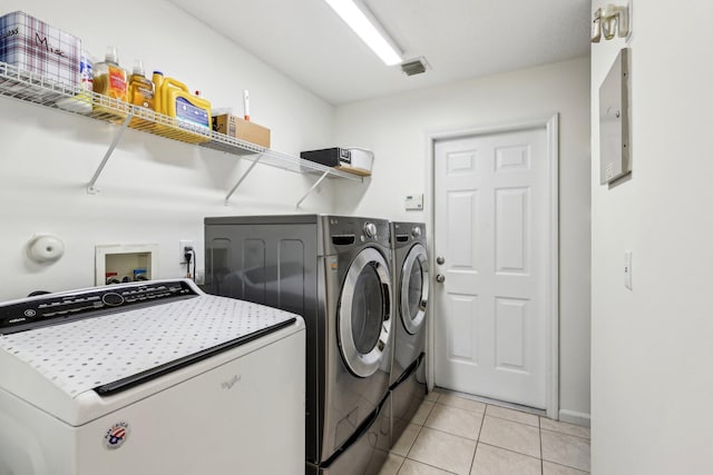 laundry area featuring laundry area, visible vents, washer and clothes dryer, and light tile patterned floors