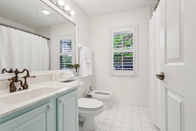 bathroom featuring tile patterned flooring, vanity, toilet, and a healthy amount of sunlight