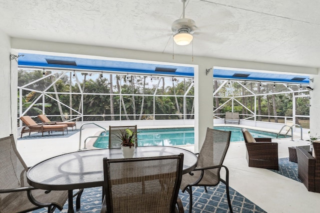 pool with a patio, glass enclosure, and a ceiling fan