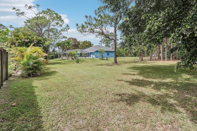 view of yard with a lanai and fence