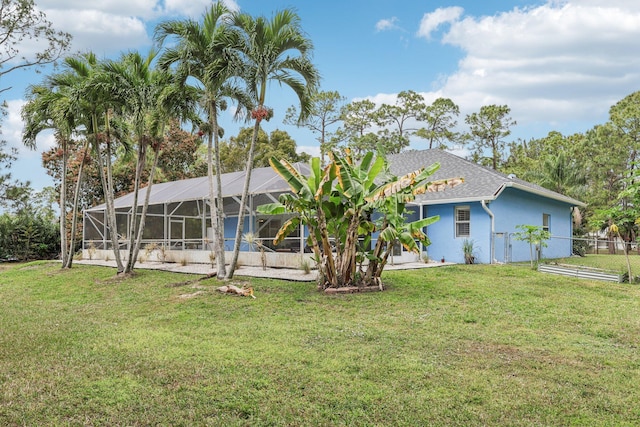 rear view of house featuring glass enclosure, stucco siding, fence, and a lawn