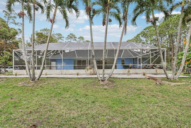 rear view of property featuring a lanai and a yard