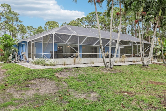 back of property with glass enclosure and a yard