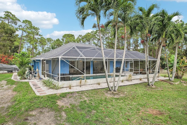 rear view of property with a lanai, an outdoor pool, a patio, and a yard