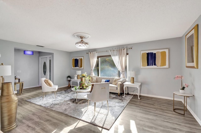 living room with visible vents, baseboards, and wood finished floors