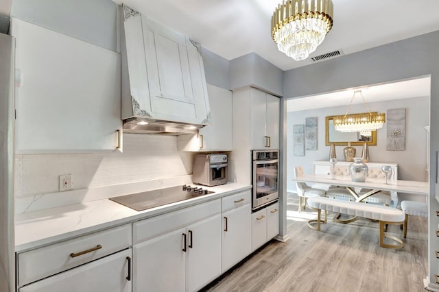 kitchen featuring visible vents, oven, black electric cooktop, light wood-type flooring, and a chandelier