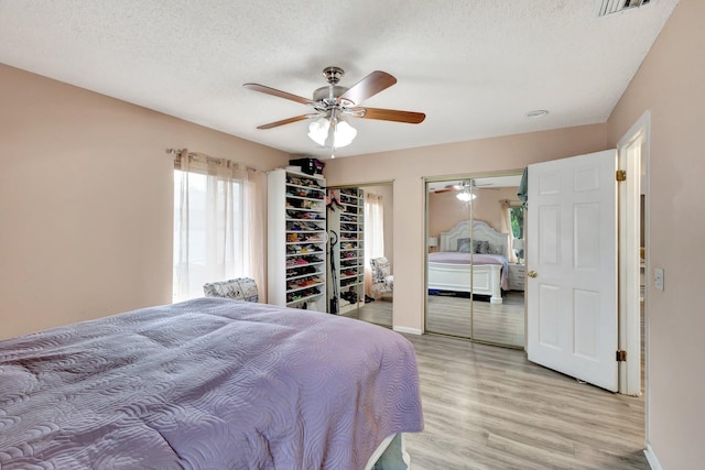 bedroom with visible vents, ceiling fan, a textured ceiling, light wood-type flooring, and baseboards