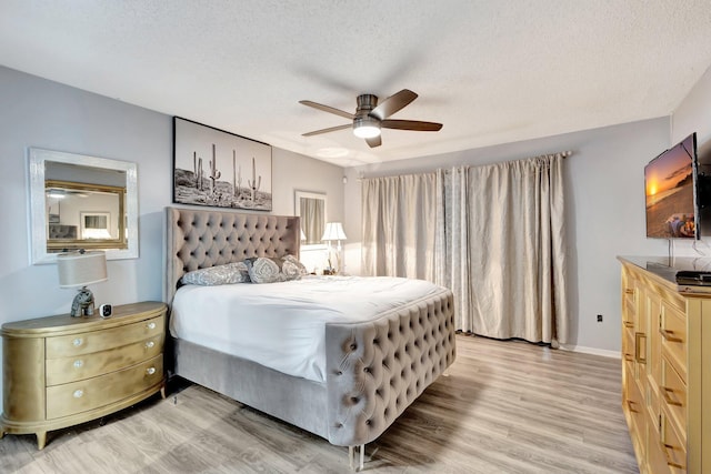 bedroom with baseboards, ceiling fan, light wood-style flooring, and a textured ceiling