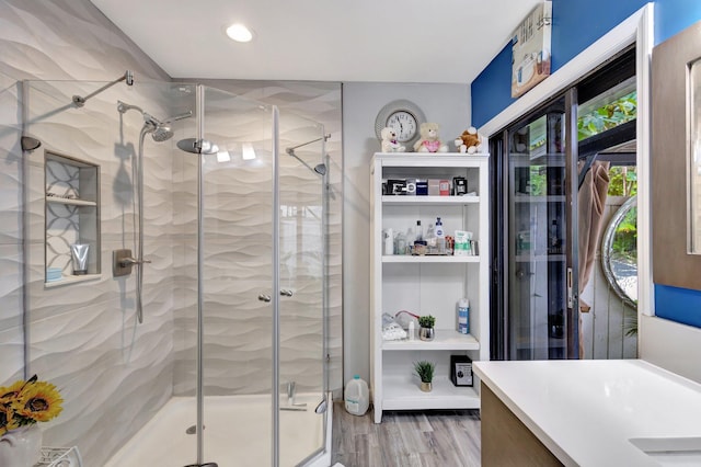 full bath with a stall shower, vanity, and wood finished floors