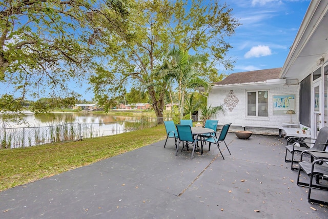 view of patio with outdoor dining area, a water view, and fence