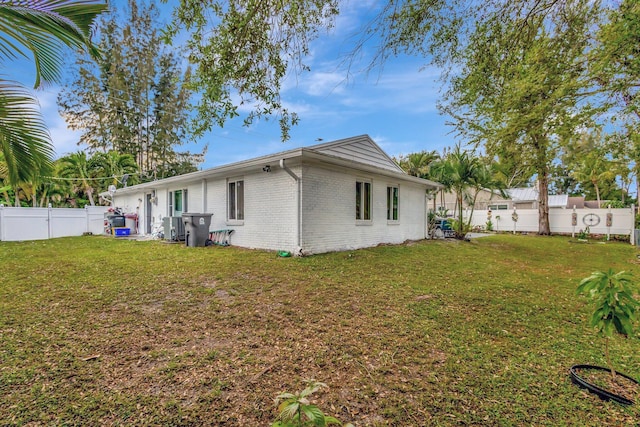 back of house with brick siding, a lawn, central AC unit, and a fenced backyard