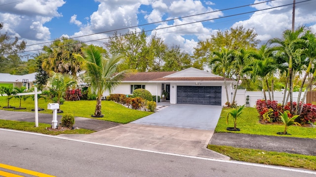 ranch-style house featuring stucco siding, an attached garage, a front yard, fence, and driveway