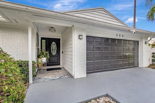 view of exterior entry with brick siding and an attached garage