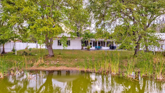 rear view of property with a patio area, a yard, a water view, and fence