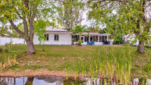 back of property featuring a sunroom, brick siding, a yard, and fence