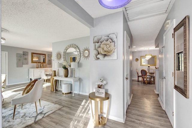 hall featuring a textured ceiling, wood finished floors, and baseboards