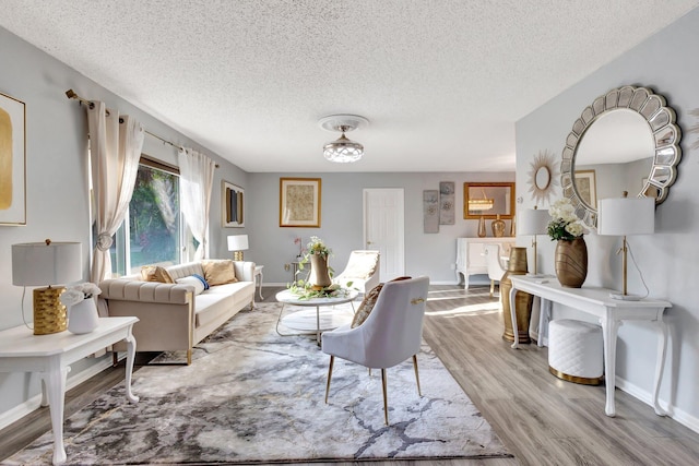 living room with light wood-style flooring, baseboards, and a textured ceiling