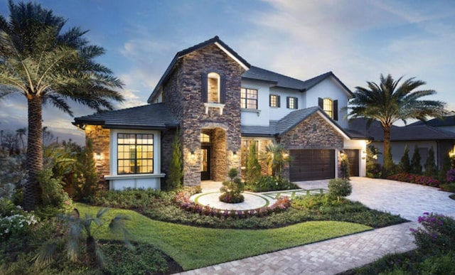 view of front of property with a garage, stone siding, and decorative driveway