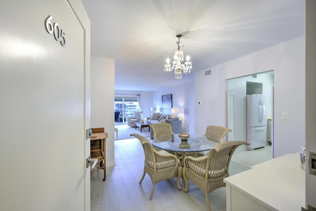 dining space featuring light wood-style floors and a notable chandelier