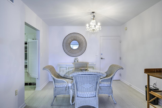 dining area with an inviting chandelier, visible vents, baseboards, and wood finished floors