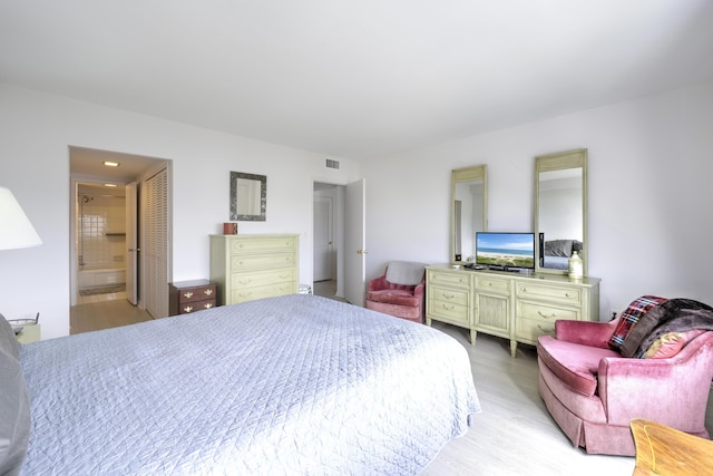 bedroom featuring light wood-type flooring, visible vents, and connected bathroom