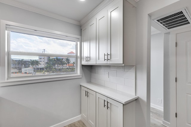 kitchen with light wood-style floors, light countertops, backsplash, and baseboards