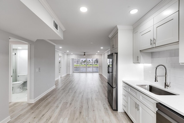 kitchen with a sink, visible vents, light countertops, appliances with stainless steel finishes, and backsplash