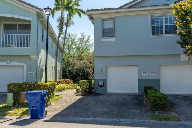 view of property exterior with stucco siding, decorative driveway, an attached garage, and a tile roof