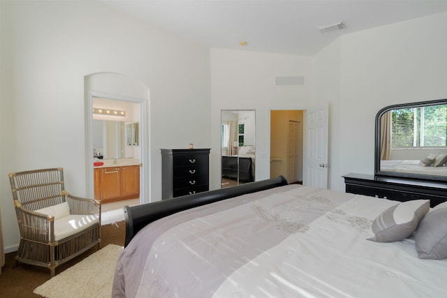 bedroom with visible vents, a high ceiling, and ensuite bath